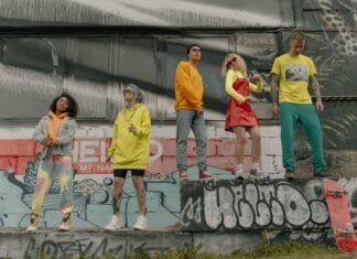 Grupa młodych osób w miejskich stylizacjach przy ścianie z graffiti