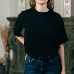 Model w czarnej koszulce i dżinsach prezentuje minimalistyczny styl